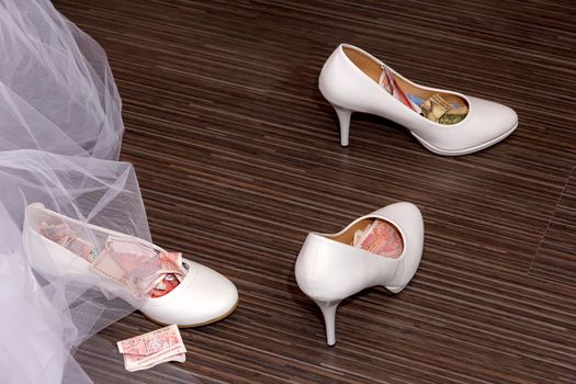 a white wedding shoes full of money and currency. ritual at some weddings-the shoe is filled with money then the bride is given to the groom.