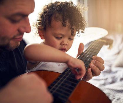 Cropped shot of a father teaching his baby daughter all about the guitar.