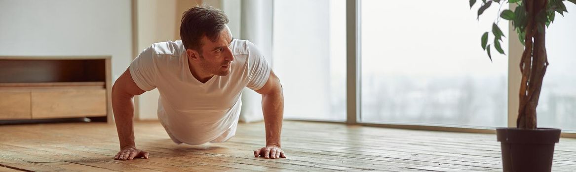 Strong man doing plank at home alone