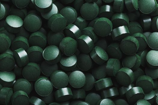 Dark Green round tablets of organic spirulina as a texture