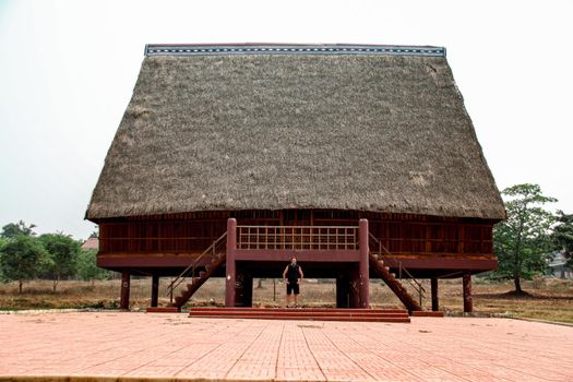 A tourist exploring a traditional architecture of a Bahnar ethnic stilt house