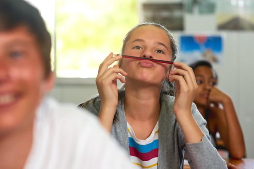 Classroom shenanigans. Shot of a young schoolgirl pulling a funny face while sitting in class.