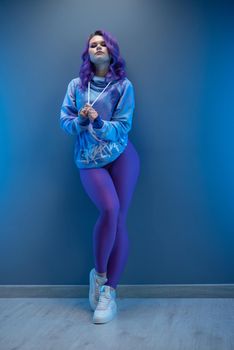 a girl in stylish purple sportswear and with purple hair poses sexually
