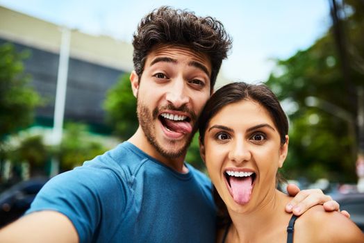 Lets snap some silly selfies before we start sweating. Portrait of a sporty young couple taking a selfie together outdoors.