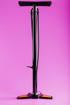 Black bicycle manual air pump for pumping wheels on a pink background