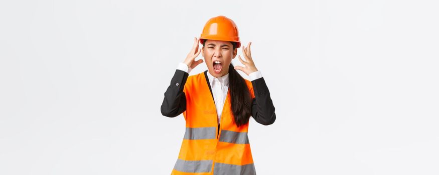 Mad and outraged asian female chief engineer, construction manager burst in rage, losing temper at employees, shouting and shaking hands aggressive, scream furious as scolding someone