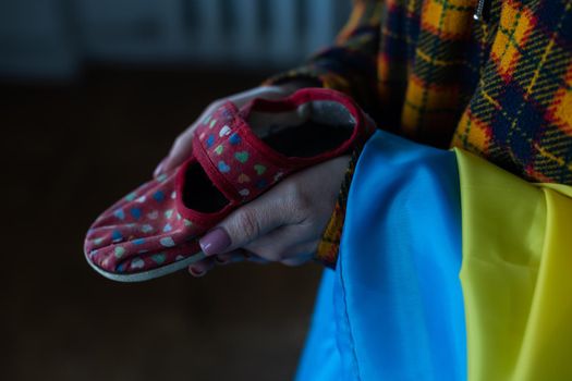 Childrens slippers in mothers hands. War in Ukraine.