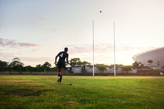 Score. Full length shot of an unrecognizable sportsman kicking a rugby ball during an early morning training session.