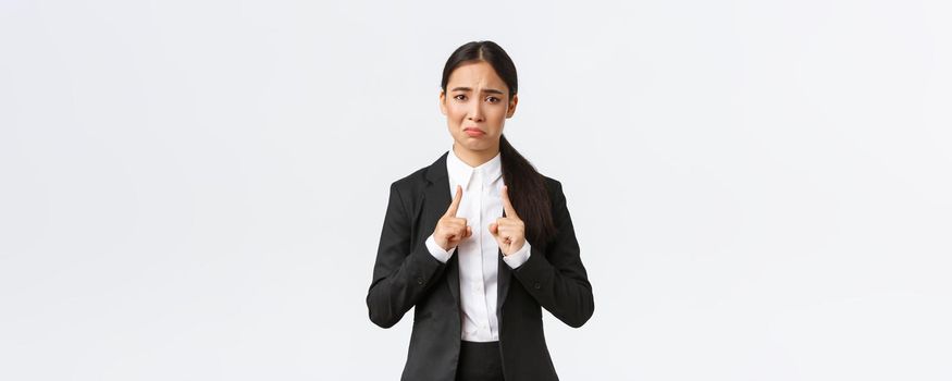 Upset and pouting asian saleswoman complaining on small size. Female office manager looking displeased and showing something tiny, little and disappointing, white background