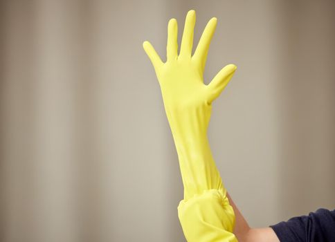 Time to get this spring cleaning done. Shot of a young woman applying cleaning rubber gloves.
