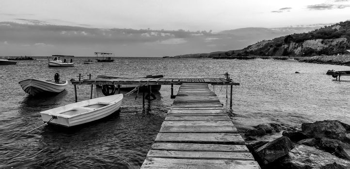 Black and white panoramic view of wooden pier and  boats 