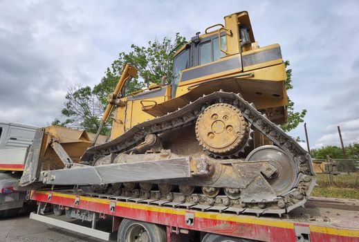 Trailer truck with long platform transport the Excavator. Earth mover backhoe on heavy duty flatbed vehicle for transported.