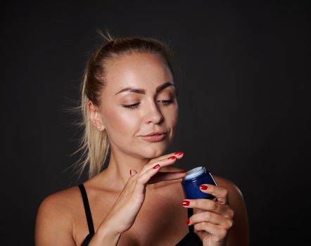 Closeup stunning beautiful middle aged European blonde woman applying face moisturizer, smoothing serum, taking care of facial skin. Cosmetic procedures against wrinkles, spa, wellness, youth concept