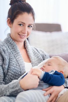 Portrait of a mother holding her sleepy baby boy at home.