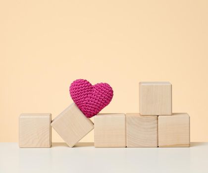 Red knitted heart and wooden cubes. Donation concept, love
