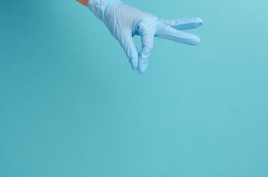 Doctor's hand in a blue medical glove holds an object on a blue background