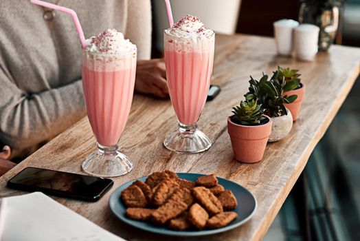 Out for some refreshments. Cropped shot of an unrecognizable woman having a milkshake and cookies with her friend at a cafe.
