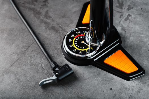 Air pump with a manometer and a wheel inflation hose on a dark background with free space