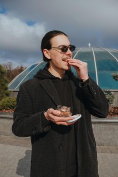 Young gay hipster eating peanuts at the street smiling happy sunglasses