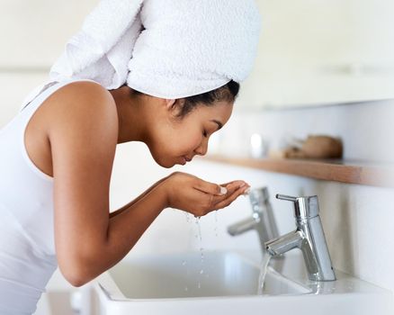 My skin care routine. Shot of a young woman washing her face at the bathroom sink.