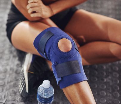 Dealing with injury. Shot of a sportswoman wearing a knee brace.