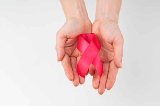 Female hands with a red ribbon on a white background. Symbol of the fight against AIDS. Copy space.
