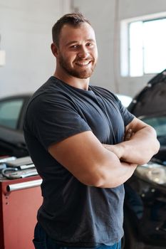 Ill have your car running like new again. Shot of a mechanic posing with his arms crossed in an auto repair shop.