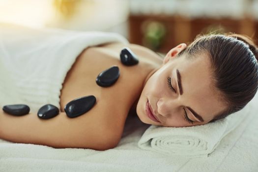Shot of an attractive young woman getting a hot stone massage at a beauty spa.
