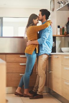 Sealed with a kiss. Shot of an affectionate young man kissing his girlfriend on the forehead in their kitchen.