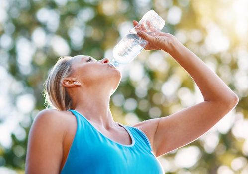 Always stay hydrated during your workouts. Low angle shot of a mature woman drinking water out of a bottle outdoors.
