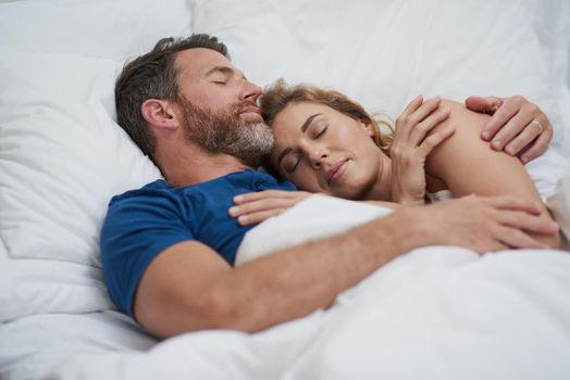 Love makes the sweetest embrace. Shot of a happy middle aged couple relaxing in bed together.