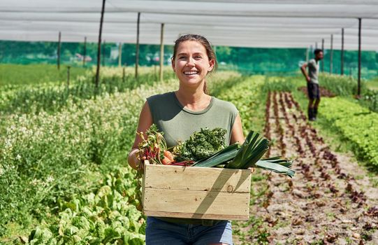 Fresh produce coming right up. Portrait of an attractive young woman carrying a crate full of vegetables outdoors on a farm.