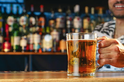Barman serves glass of cold beer at bar counter in pub
