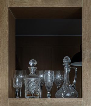 Traditional wine glass pitcher with Wine glass and Crystal decanter and Glass stopper in Square wooden frame Interior. Crystal and glassware set, Selective focus.