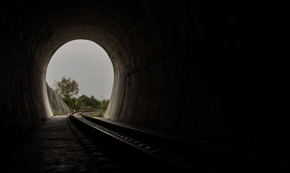Inside the railroad tunnel and railways with natural light at the end. Light at the end of the tunnel, Lights and shadows, Concept of achieving your goals, Copy space, Selective focus.