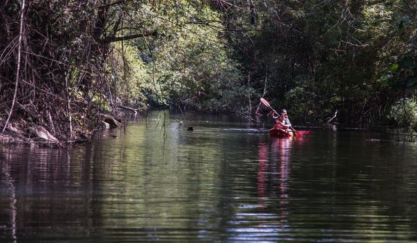 Nakhon Ratchasima, Thailand. Mar - 20, 2022 : Two young woman adventurous people having fun together while red kayaking on brook in forest. Having fun in leisure activity, Nature and Tourist attraction concept. No focus, specifically.