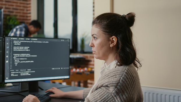 Portrait of focused software engineer writing code looking at multiple computer screens