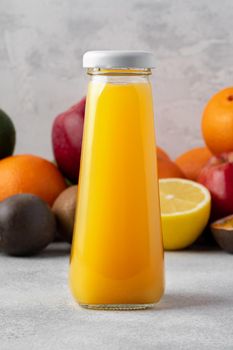 Various fruits and freshly squeezed fruits juice in bottle on gray background