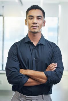You decide how far you go. Cropped portrait of a handsome young businessman standing with his arms folded in the office.