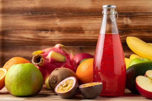 Fruit drink in glass bottle and frsh fruits on wooden background, close up
