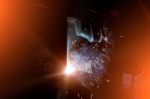 A worker electric welder cooks steel in a semi-automatic factory.