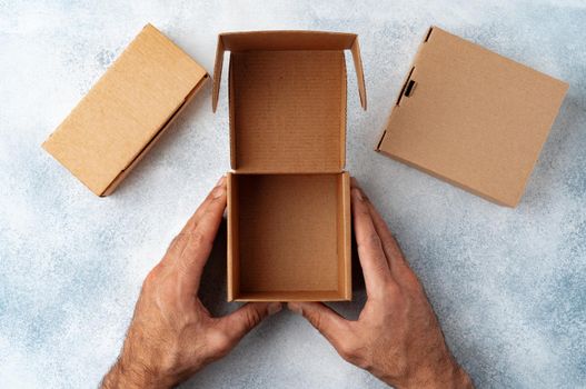 Parcel cardboard box in a man hands on a gray table background