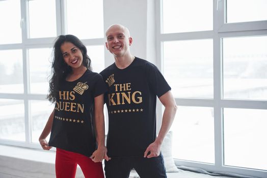 Golden colored inscriptions. The king and his queen. Man and woman in black shirts standing in the room near the windows