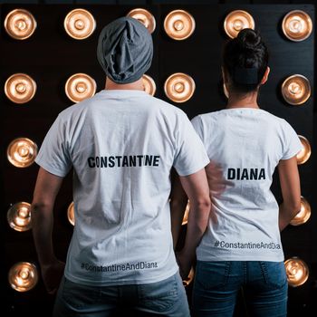 Back view of couple in shirts with their names on it standing next to studio lights