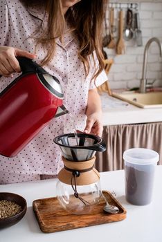young woman in lovely pajamas making coffee at home kitchen