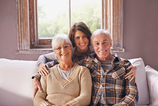 A cropped portrait of a happy senior couple and their adult daughter at home.