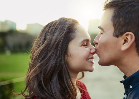 Love, nothing else needed. Shot of a young man kissing his girlfriend on the nose outdoors.