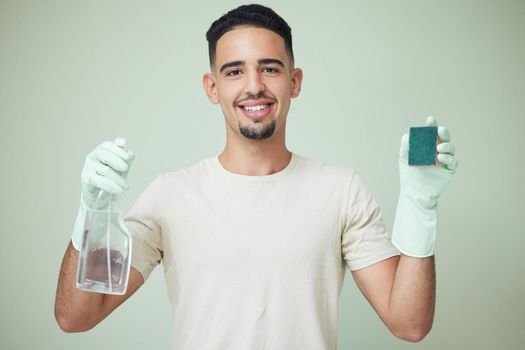 Ready to tackle the chores. Shot of a young man holding cleaning products against a green background.