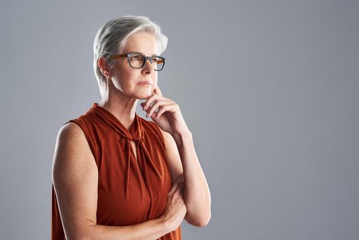 Dream big or dont dream at all. Shot of an attractive mature woman looking very thoughtful against a grey background.