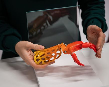 A woman demonstrates a plastic children's prosthetic hand printed on a 3D printer.